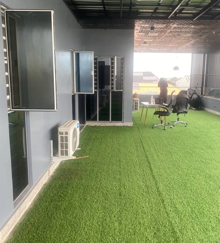 The rooftop workspace: green turf, a table and office chairs under a steel canopy
